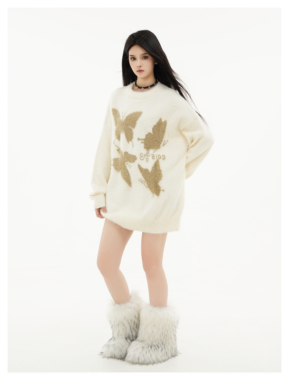 Full-length model wearing an oversized ivory sweater with tan butterfly motifs and fluffy white boots, front view.