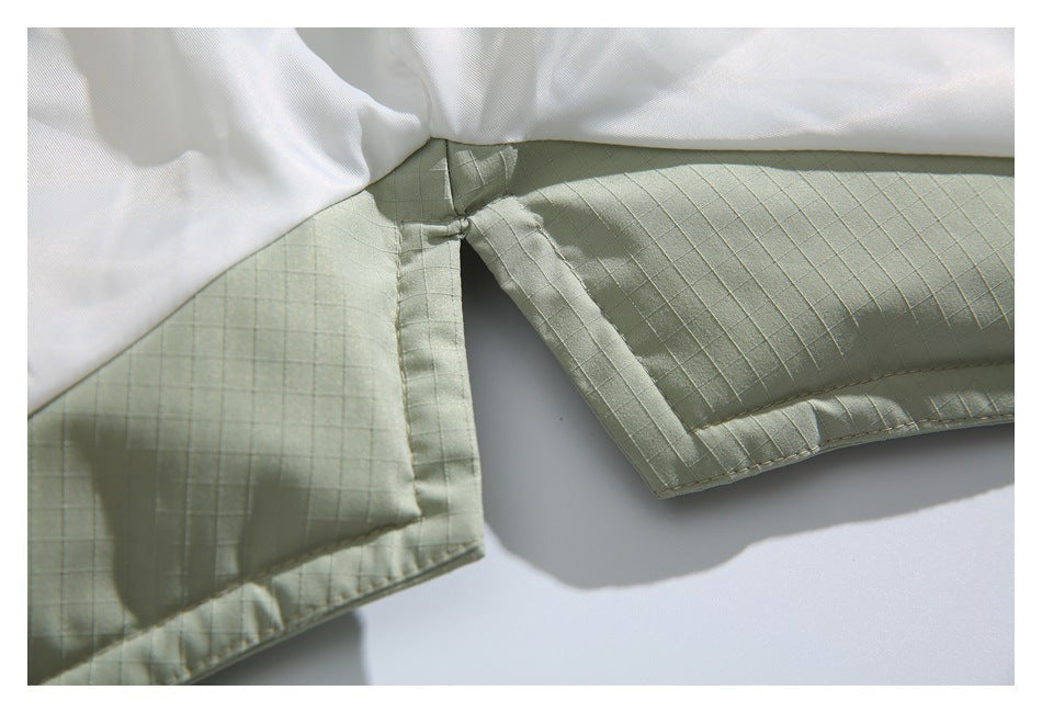 Close-up of the pale sage jacket's quilted sleeve and cuff stitching beside the white lining.