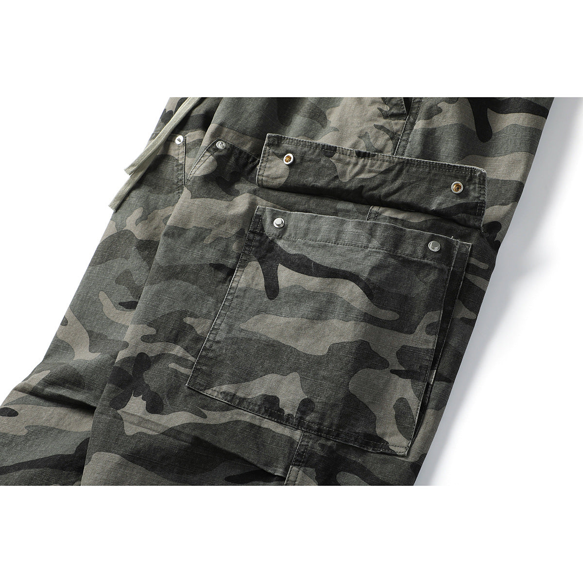 Close-up of gray and black camouflage cargo pants showing a large snap-fastened pocket and drawstrings.