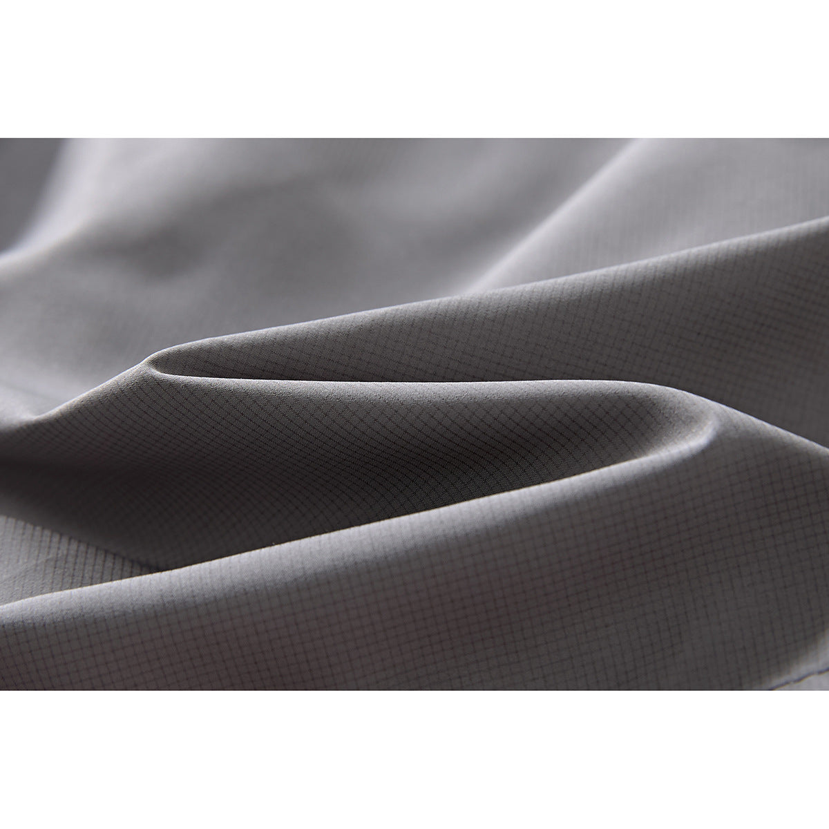 Close-up of gray fabric folded to show its fine, subtle grid texture.