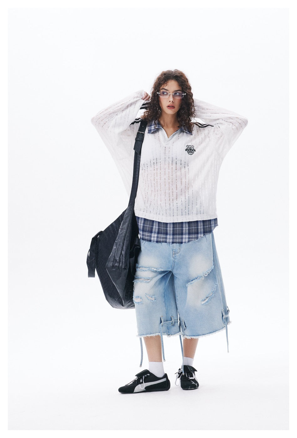 Model wearing the white plaid-trim top with arms raised, styled with light denim shorts and a black shoulder bag