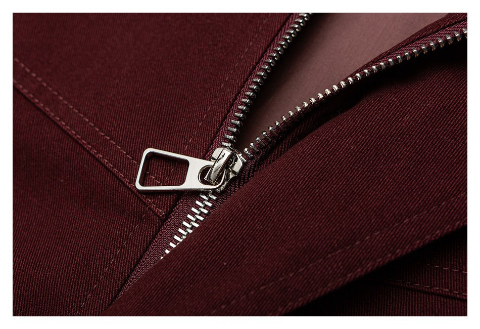 Close-up of a silver zipper on burgundy fabric, with the zipper partly open.