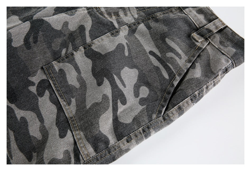 Close-up of gray and black camouflage denim pants showing a pocket edge, belt loop, and tan stitching.