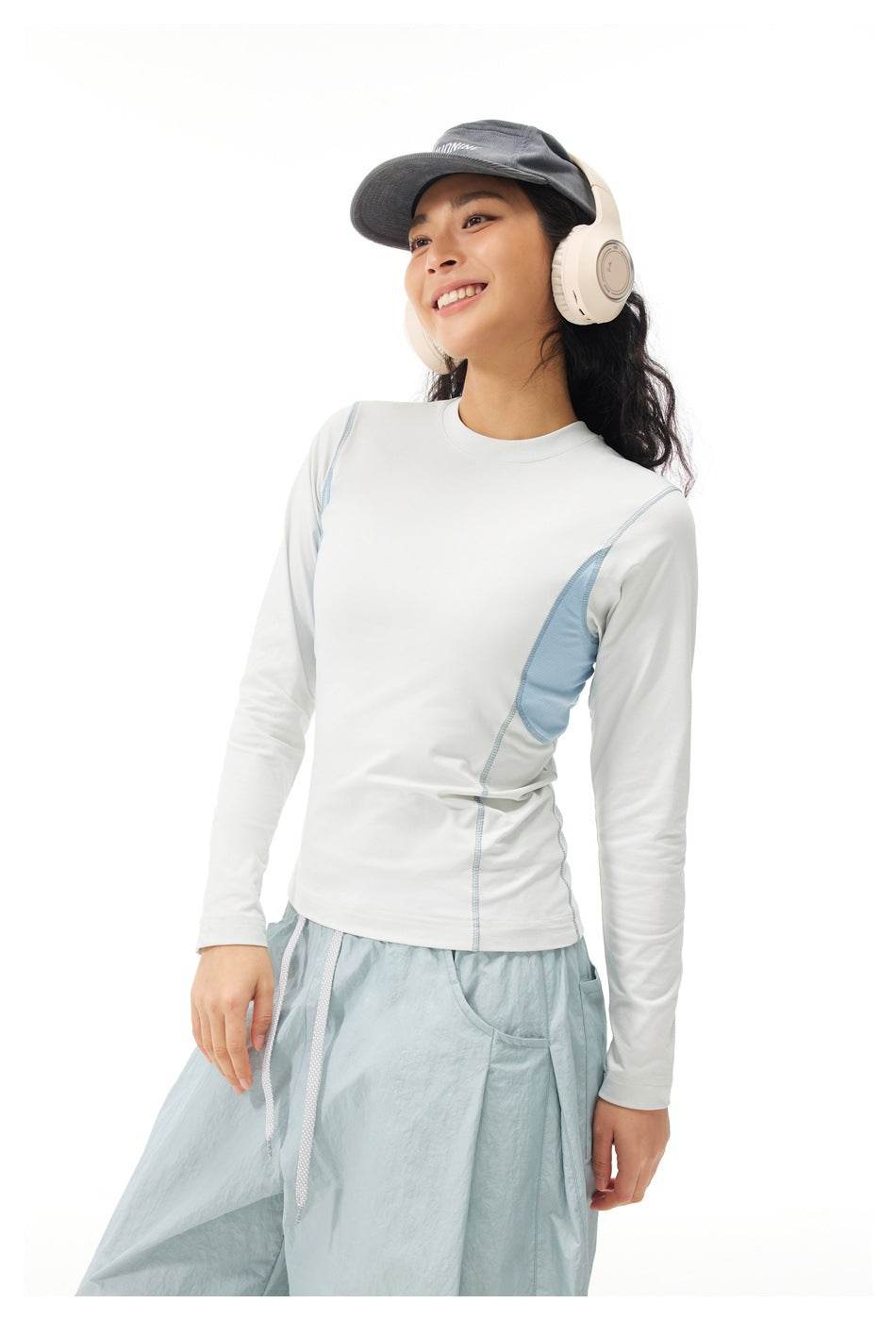 Close view of a model wearing a white long-sleeve top with pale blue side panels and pale blue pants.