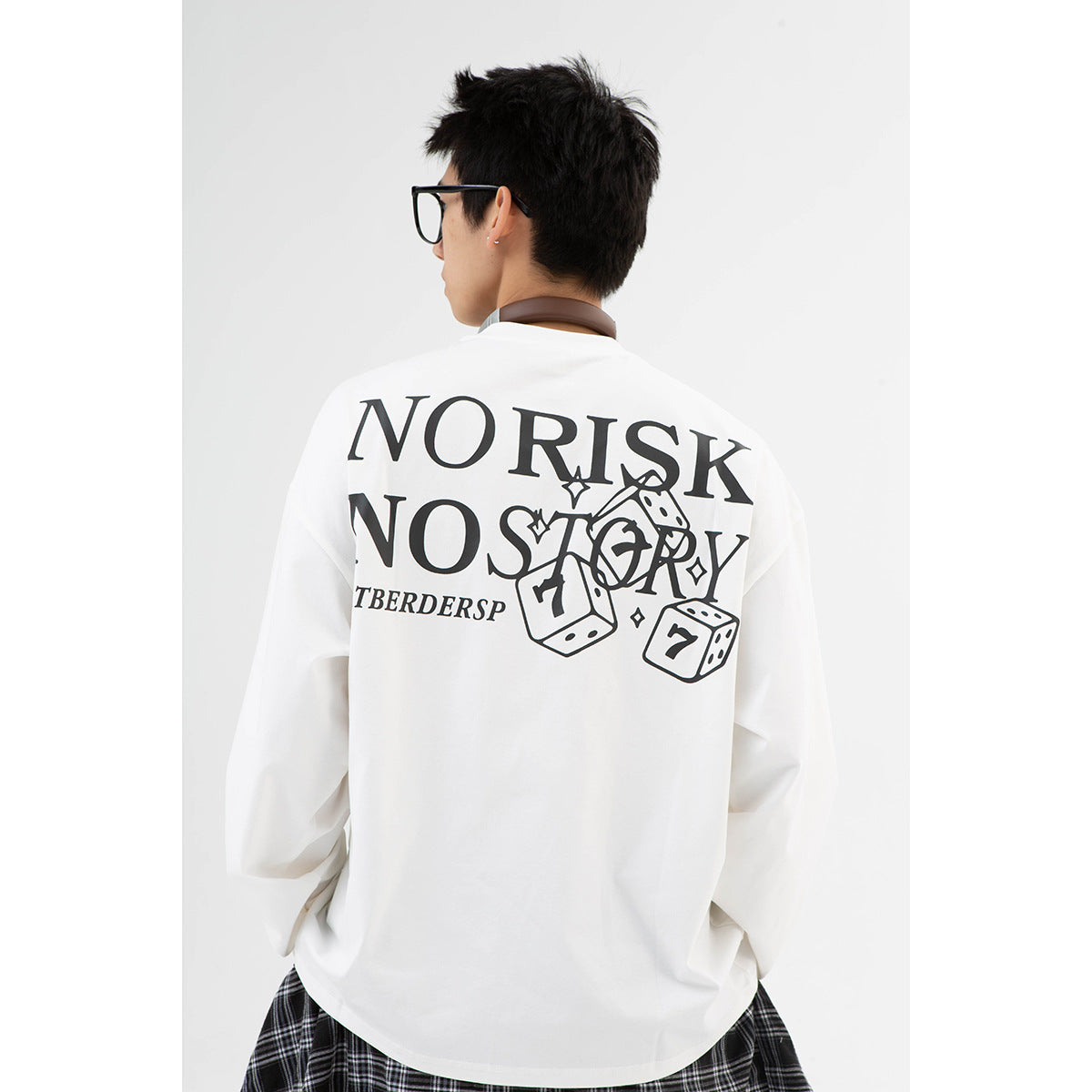 Rear view of a model wearing an oversized white long-sleeve shirt with a large black text-and-dice graphic.