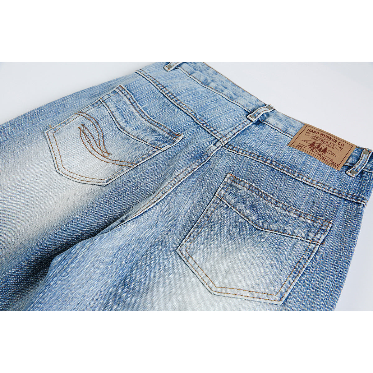 Close-up of the back pockets and waistband of light blue faded jeans, including a brown waistband patch.