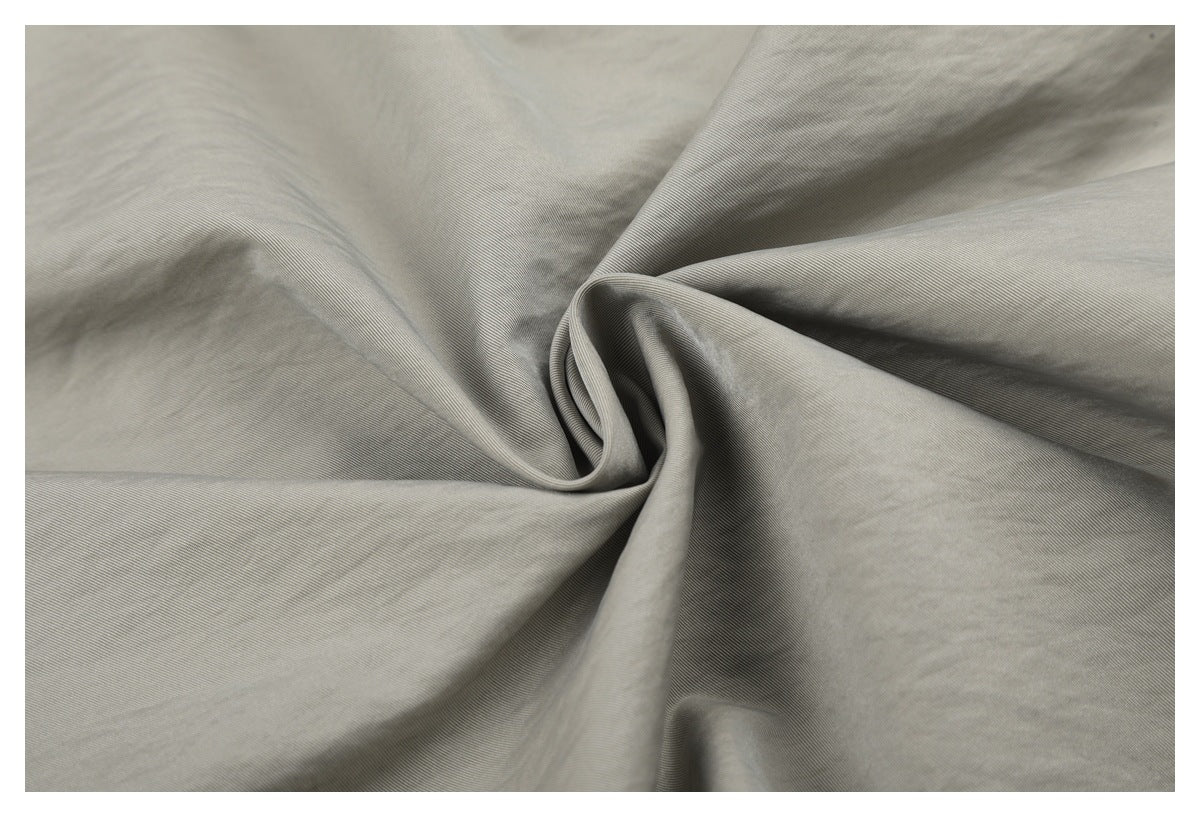 Close-up of the fine surface texture of light gray-beige trouser fabric.