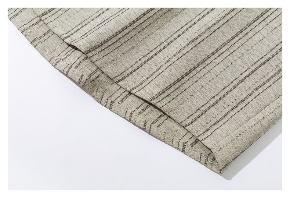 Close-up of the stitched hem of a beige shirt with thin dark stripes.