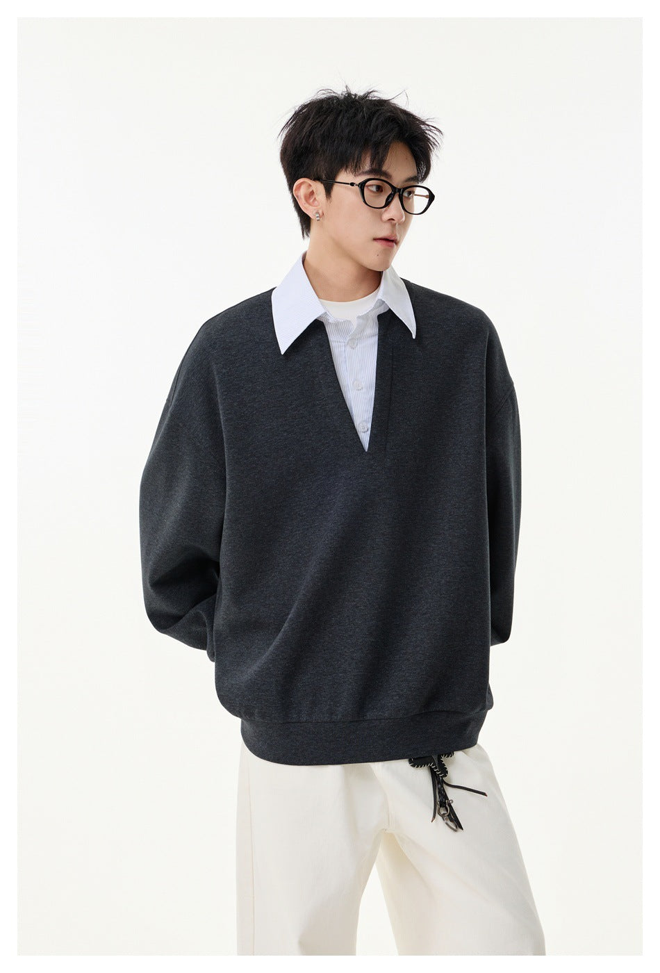 Model wearing a charcoal oversized V-neck sweatshirt layered over a white collared shirt, shown from the front.
