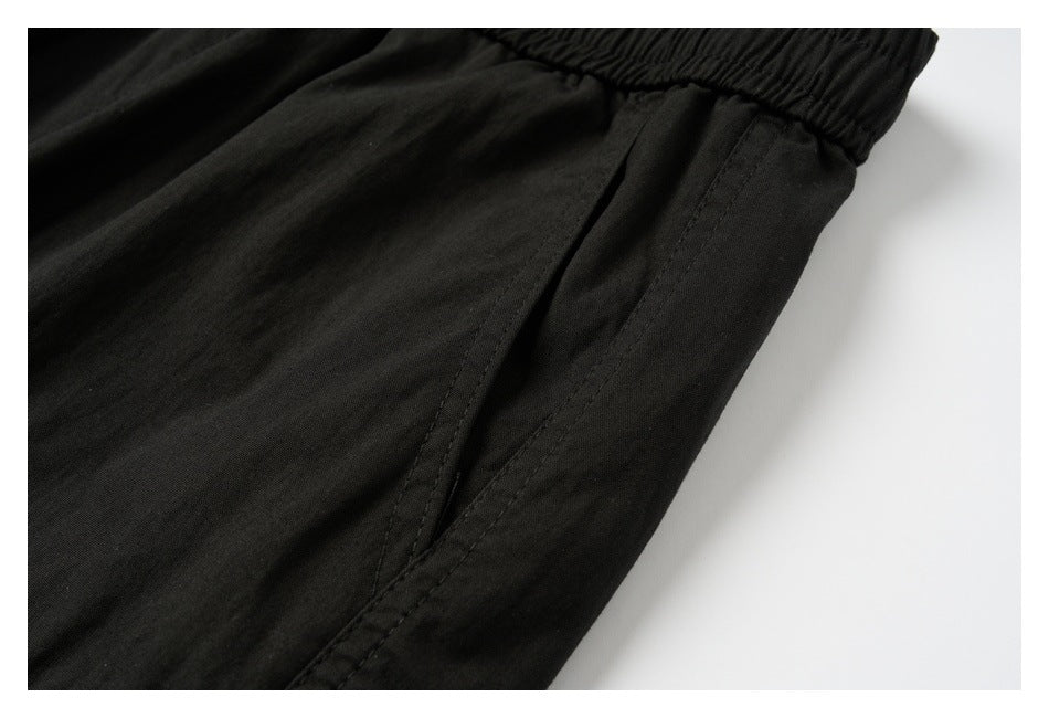 Close-up of black pants showing a side seam pocket beneath the elastic waistband.