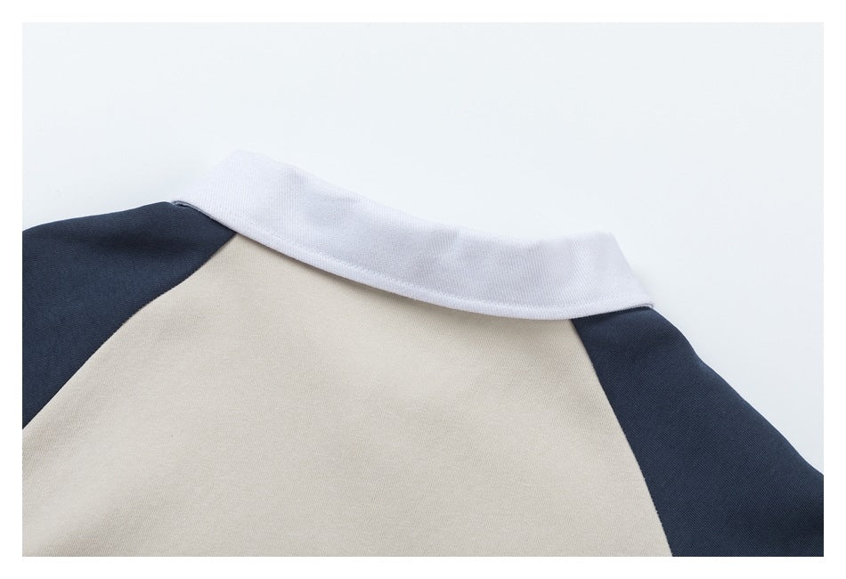 Close-up of a garment's white collar and beige back panel with dark navy shoulder panels.