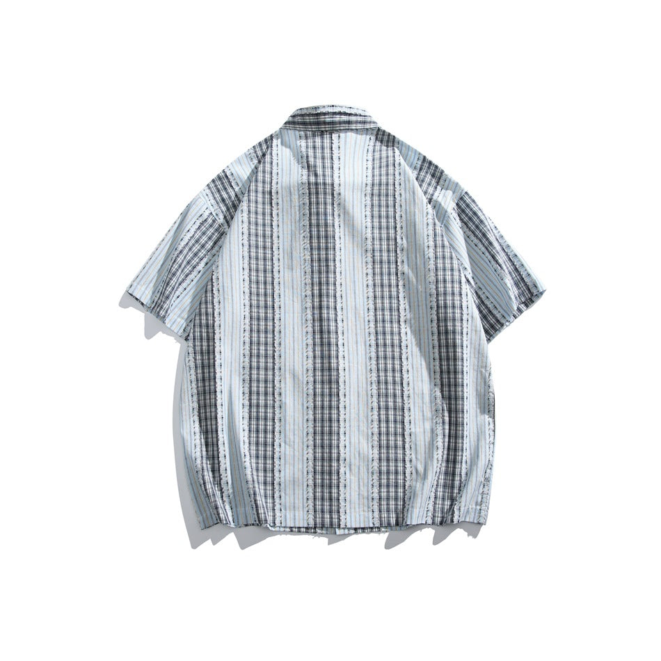 Back view of a short-sleeve shirt with vertical pale blue, navy, and white striped plaid panels.