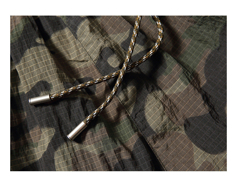 Close-up of braided drawstrings with metal tips on dark plaid pants.