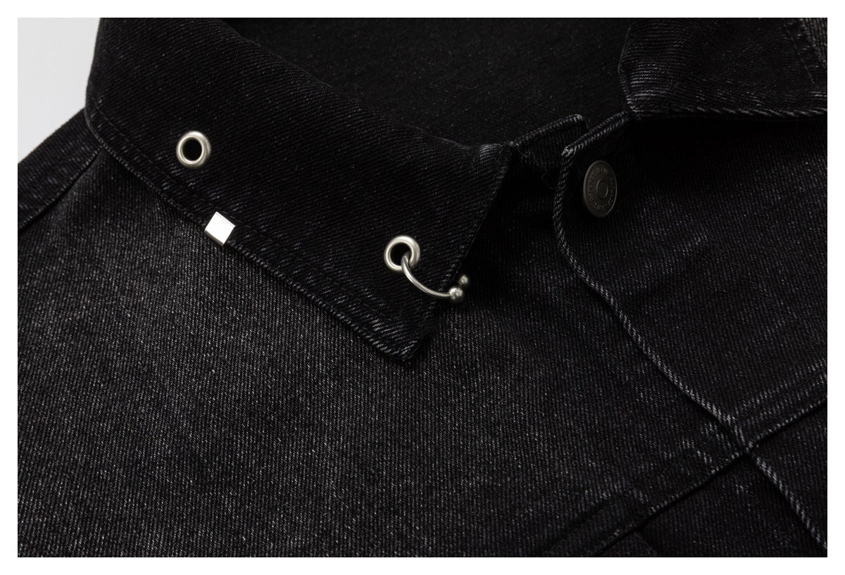 Detailed close-up of a black denim jacket collar with silver eyelets, a curved metal hook, and a button.