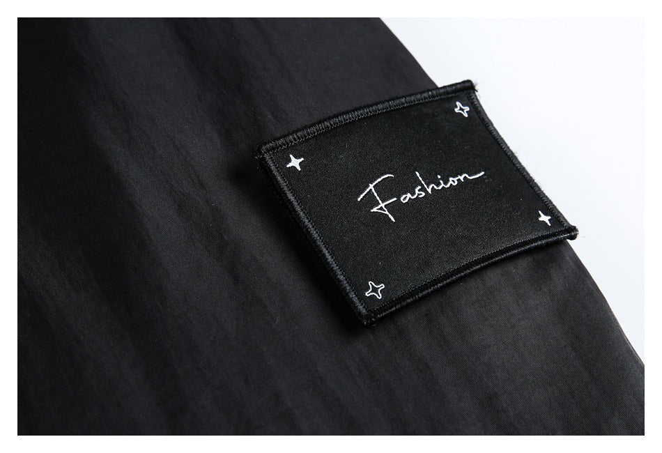 Close-up of a black garment patch embroidered with the word “Fashion” and small stars.
