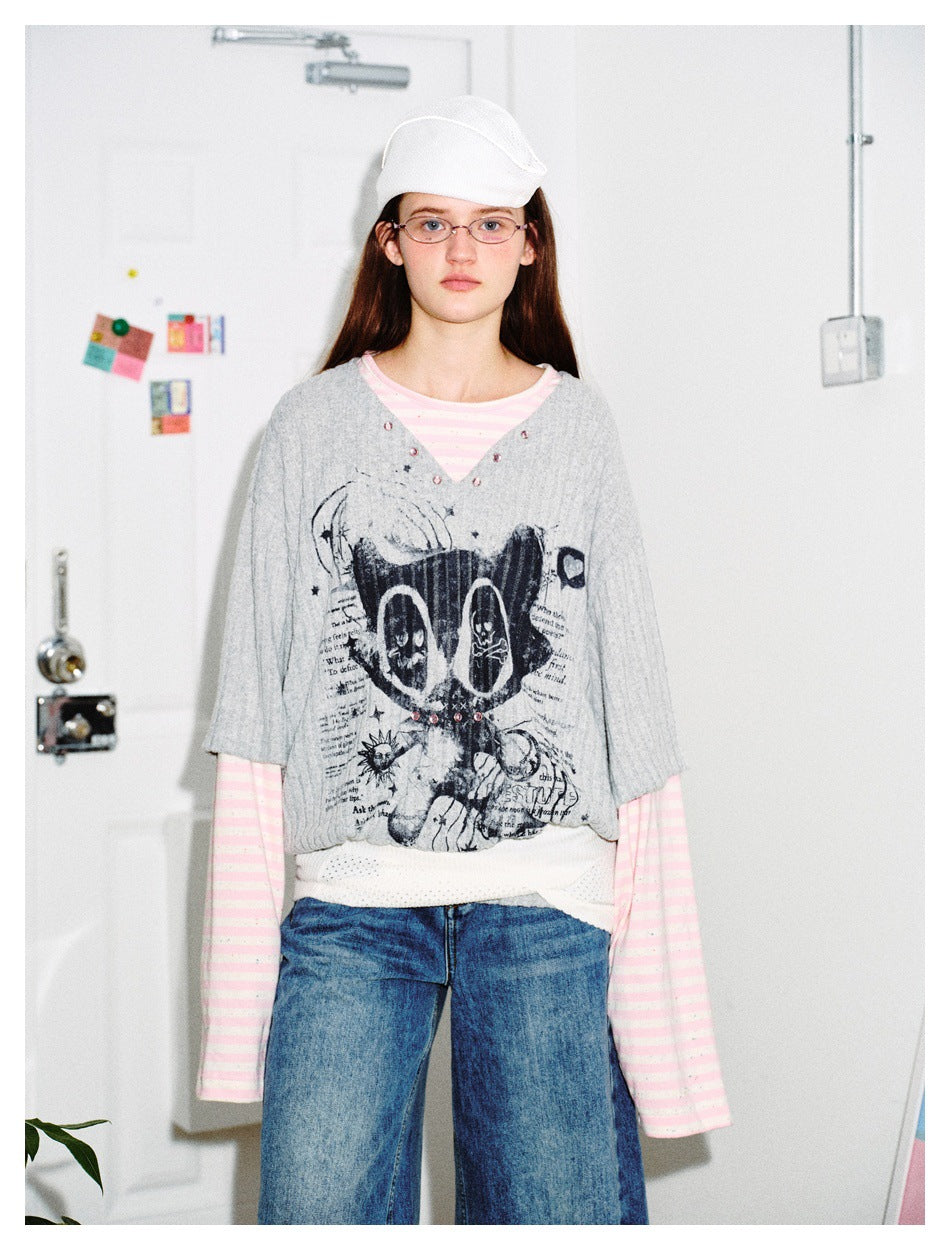 Model facing front in the gray cat-graphic layered top with pink striped long sleeves, jeans and a white cap