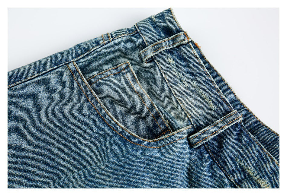 Close-up of a front pocket and belt loops on faded blue denim shorts, with small distressed marks.