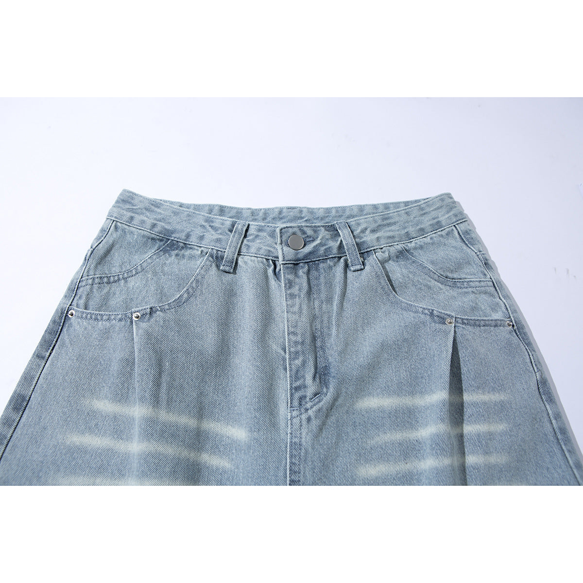 Close front view of light-wash jeans showing the waistband, button, belt loops, pockets and faded finish.