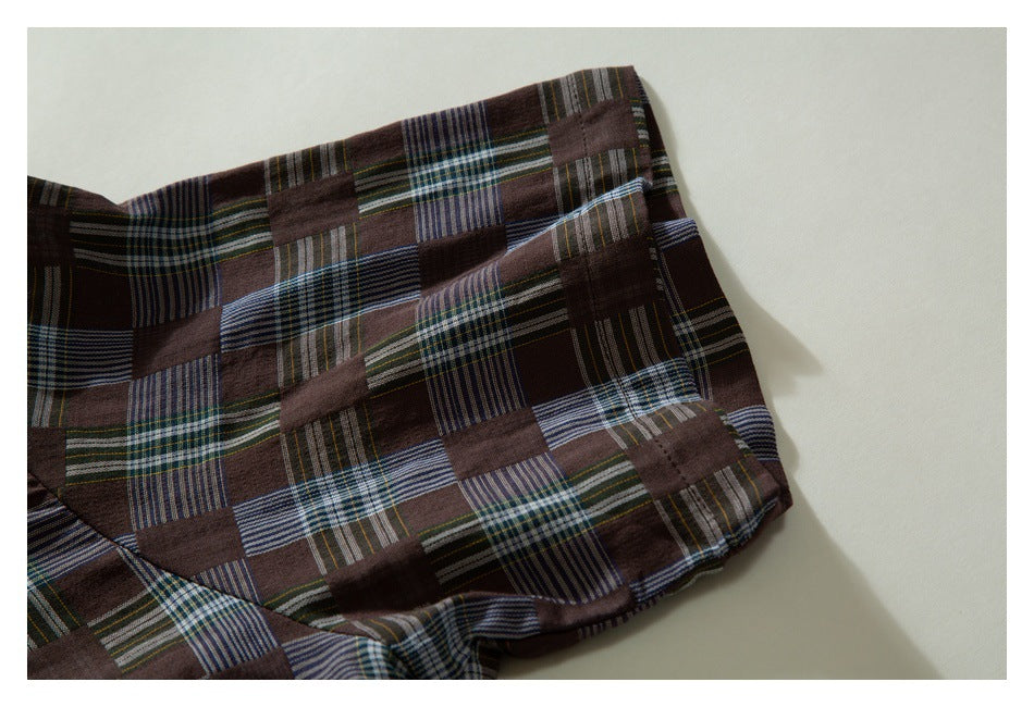 Close-up of a folded edge of the brown patchwork-plaid shirt, showing stitching and a rounded corner.