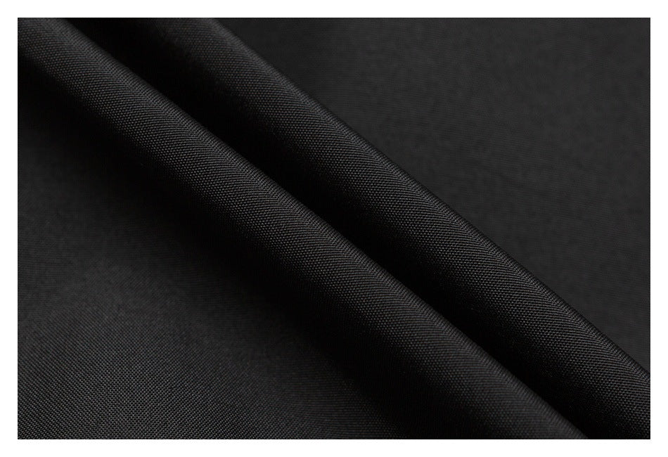 Macro view of black fabric folded to show its fine woven texture.
