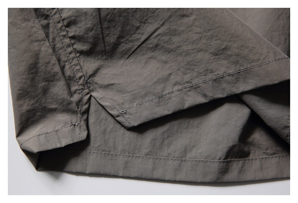 Close-up of the charcoal-gray shorts' stitched hem and overlapping fabric panels.