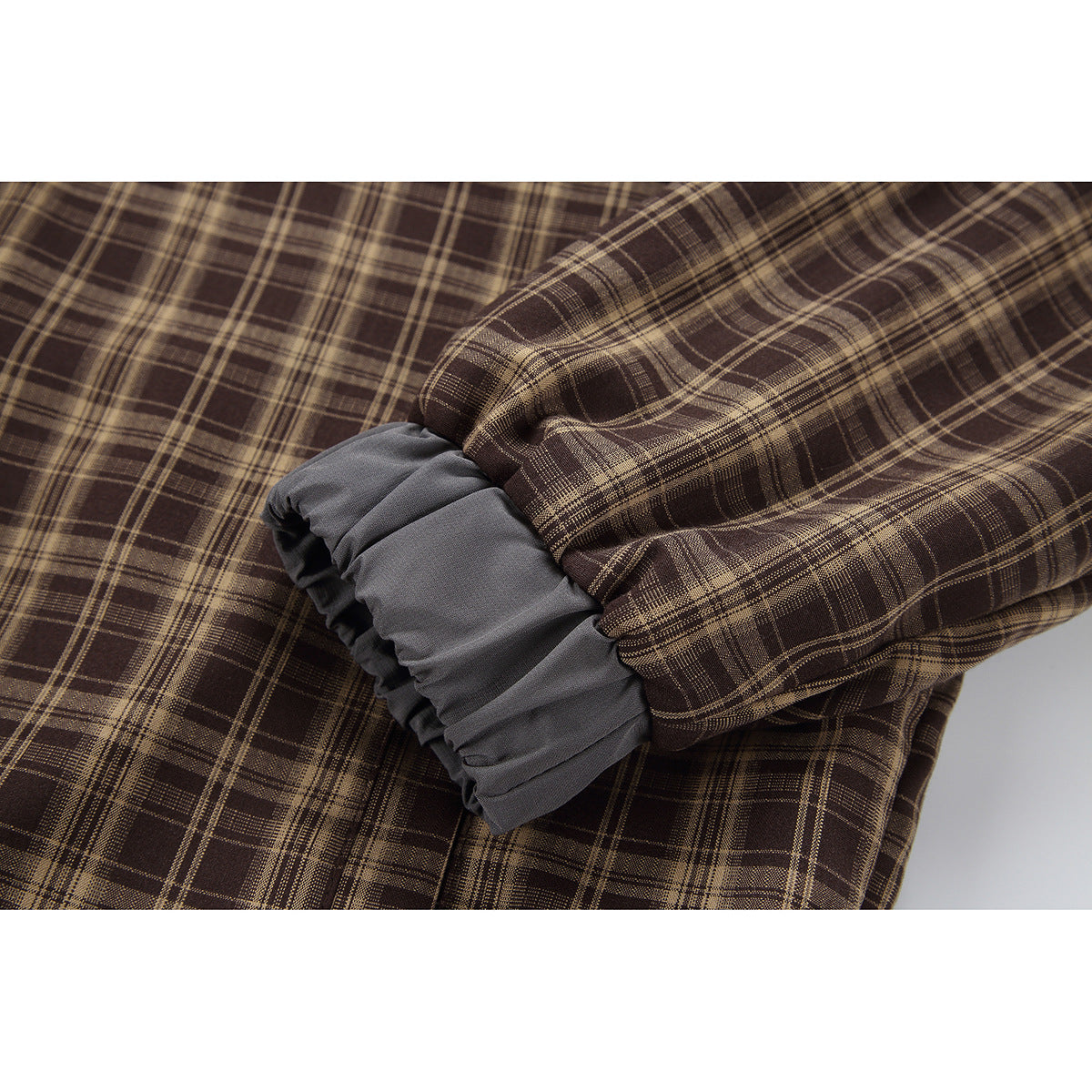 Close-up of a brown plaid jacket sleeve with a gathered gray cuff.