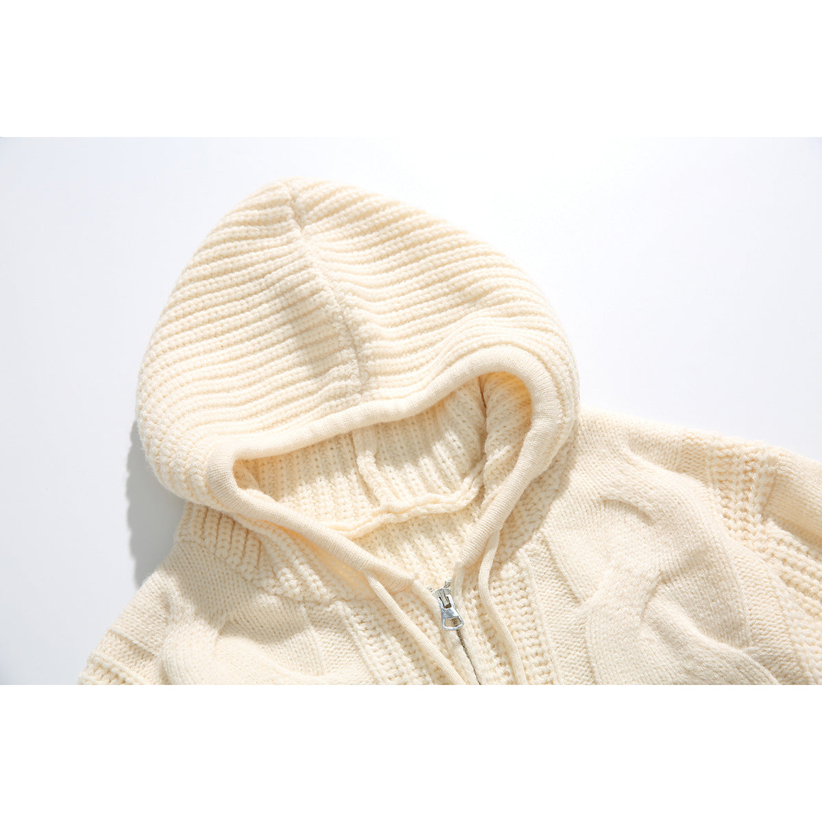 Close-up of an ivory cable-knit hood, drawstrings, and front zipper on a sweater.