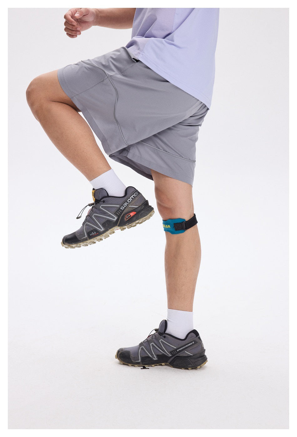 Person wearing light gray athletic shorts and a pale lavender shirt, lifting one knee to show the shorts in motion.