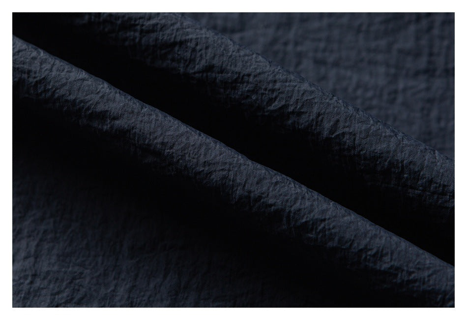 Close-up of dark fabric folded to show its crinkled texture.