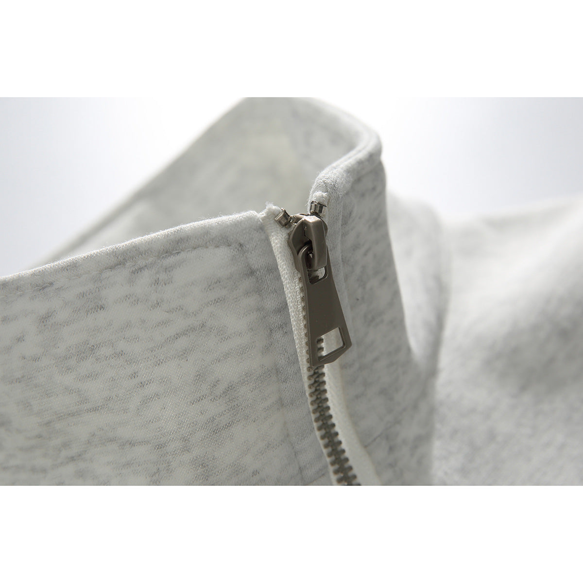 Close-up of a light gray heathered sweatshirt's metal zipper and stand collar.