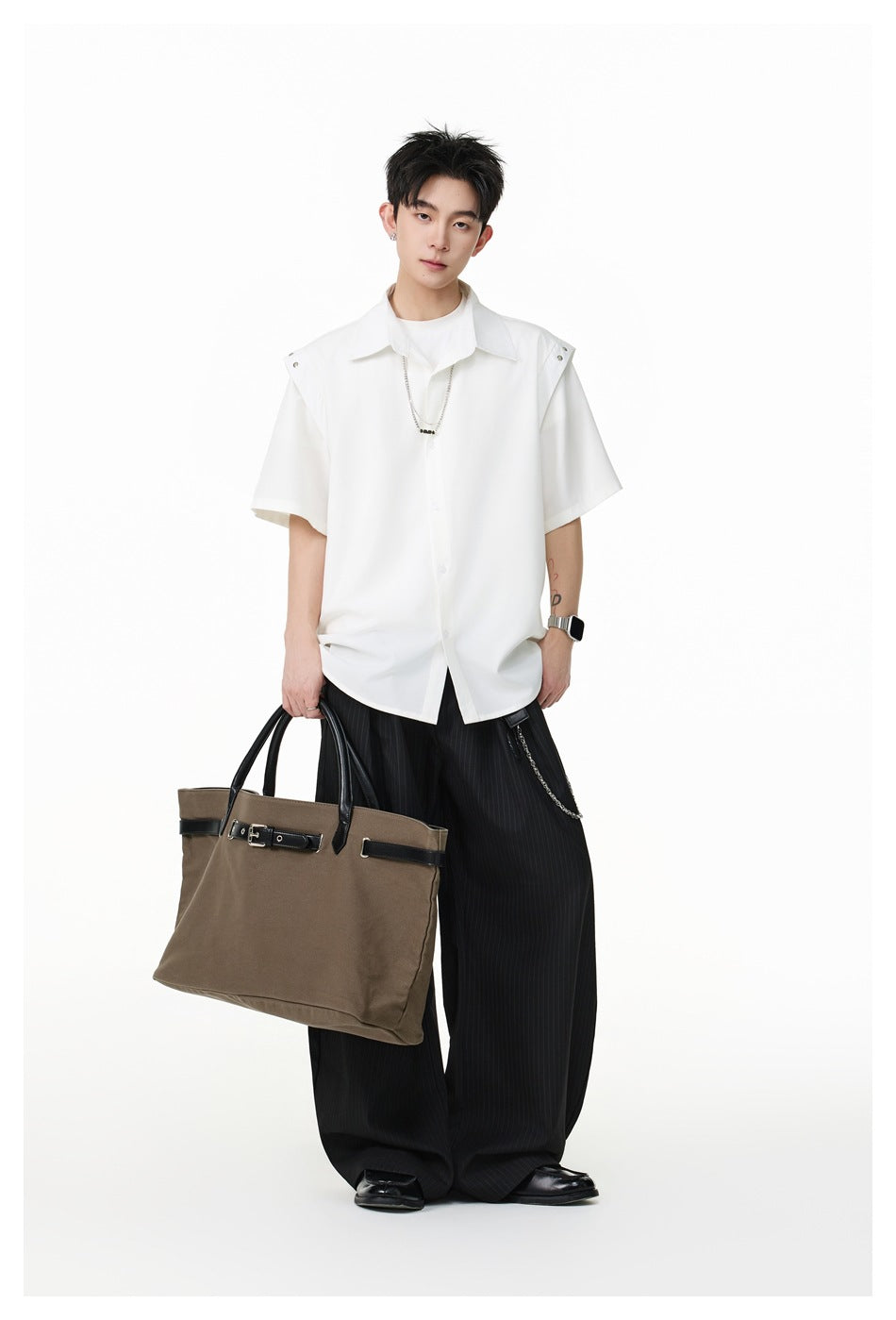 Model wearing a white short-sleeve button-up shirt with snap-detail shoulder tabs and black pinstriped wide-leg trousers.