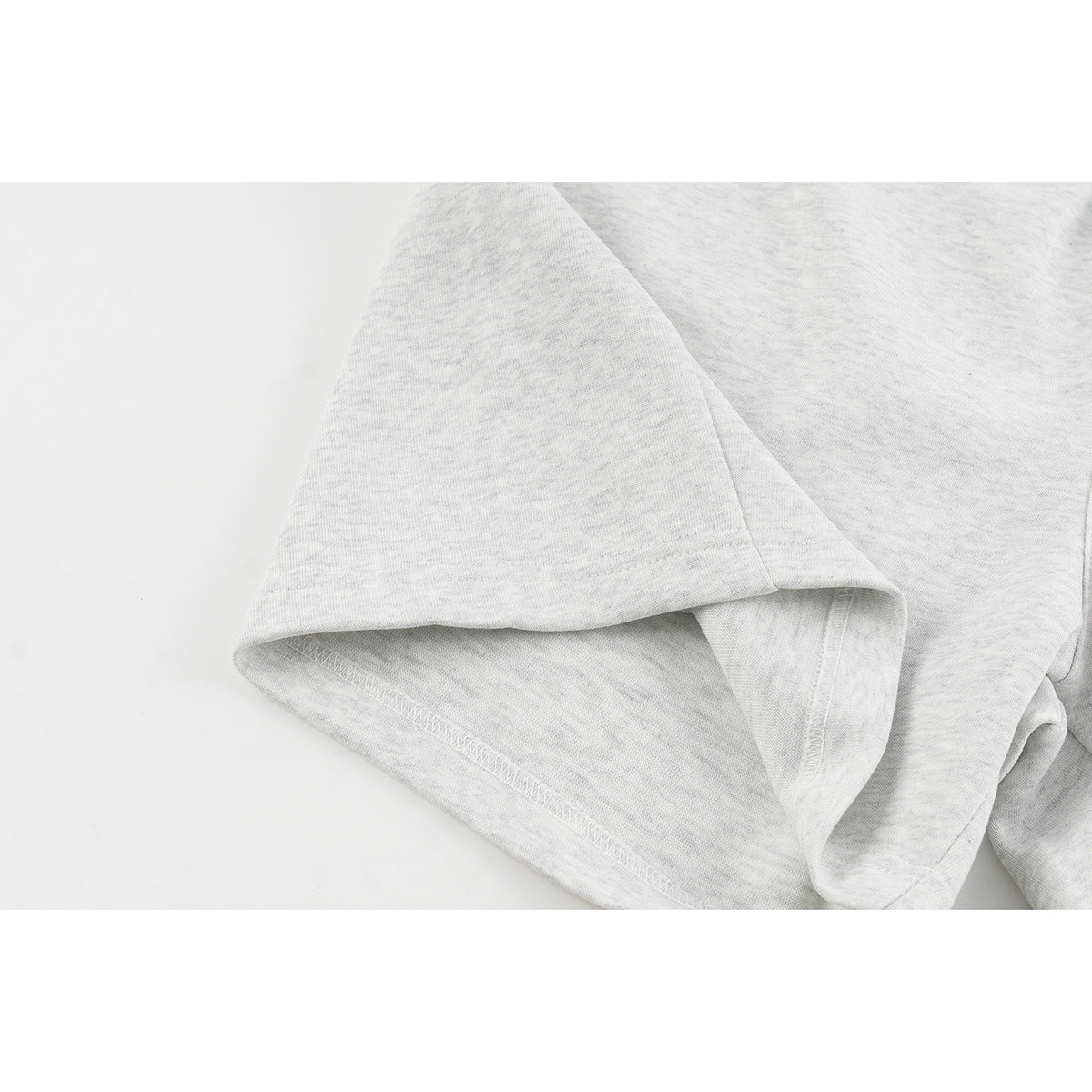 Close-up of the hem and stitched seam on light gray shorts.