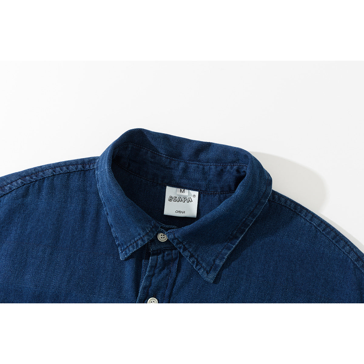 Close-up of a navy blue shirt collar, button placket, and woven label.