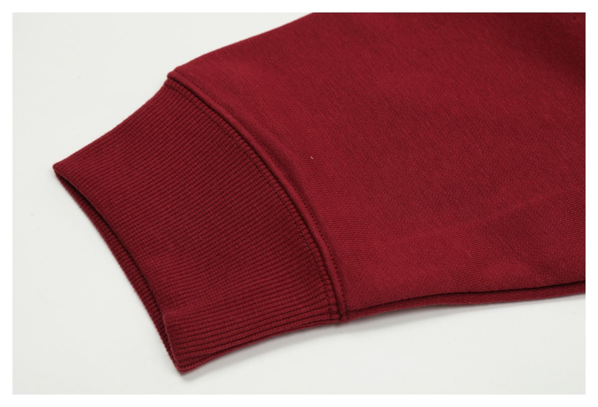 Close-up of a burgundy garment sleeve with a wide ribbed cuff and seam on a white background.