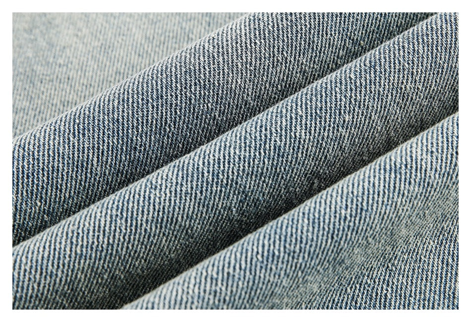 Close-up of blue-gray denim fabric with diagonal twill weave and folded ridges.