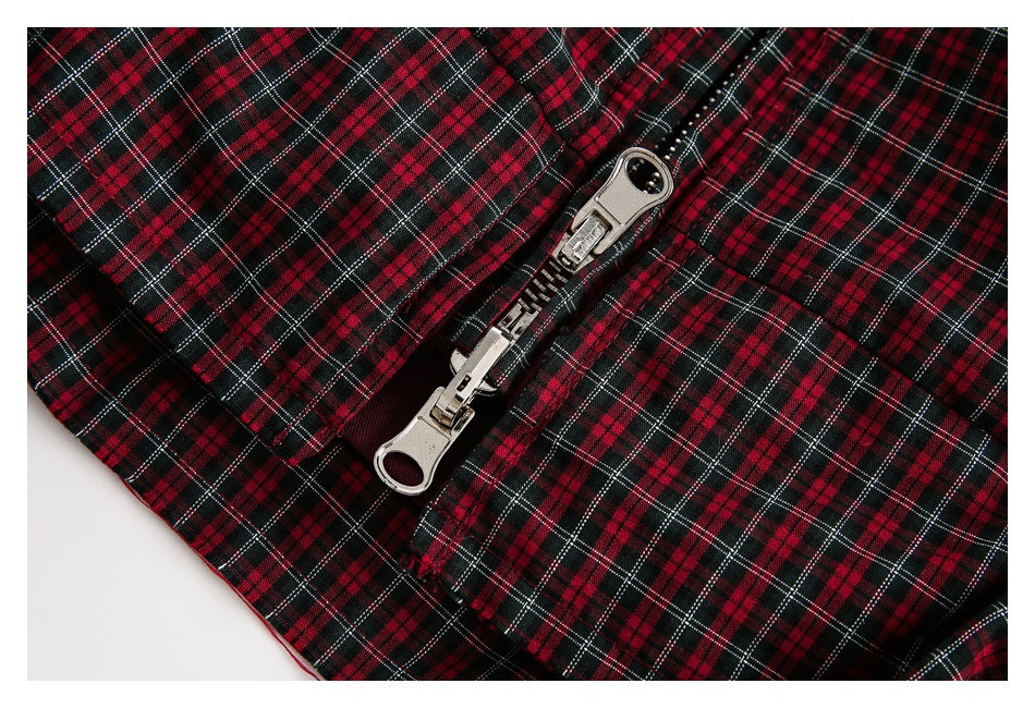 Close-up of a silver double-slider zipper on red, black, and white plaid fabric.
