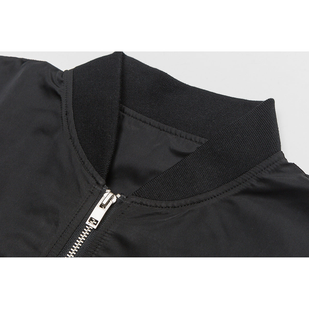 Close-up of a black jacket's ribbed collar and silver front zipper.