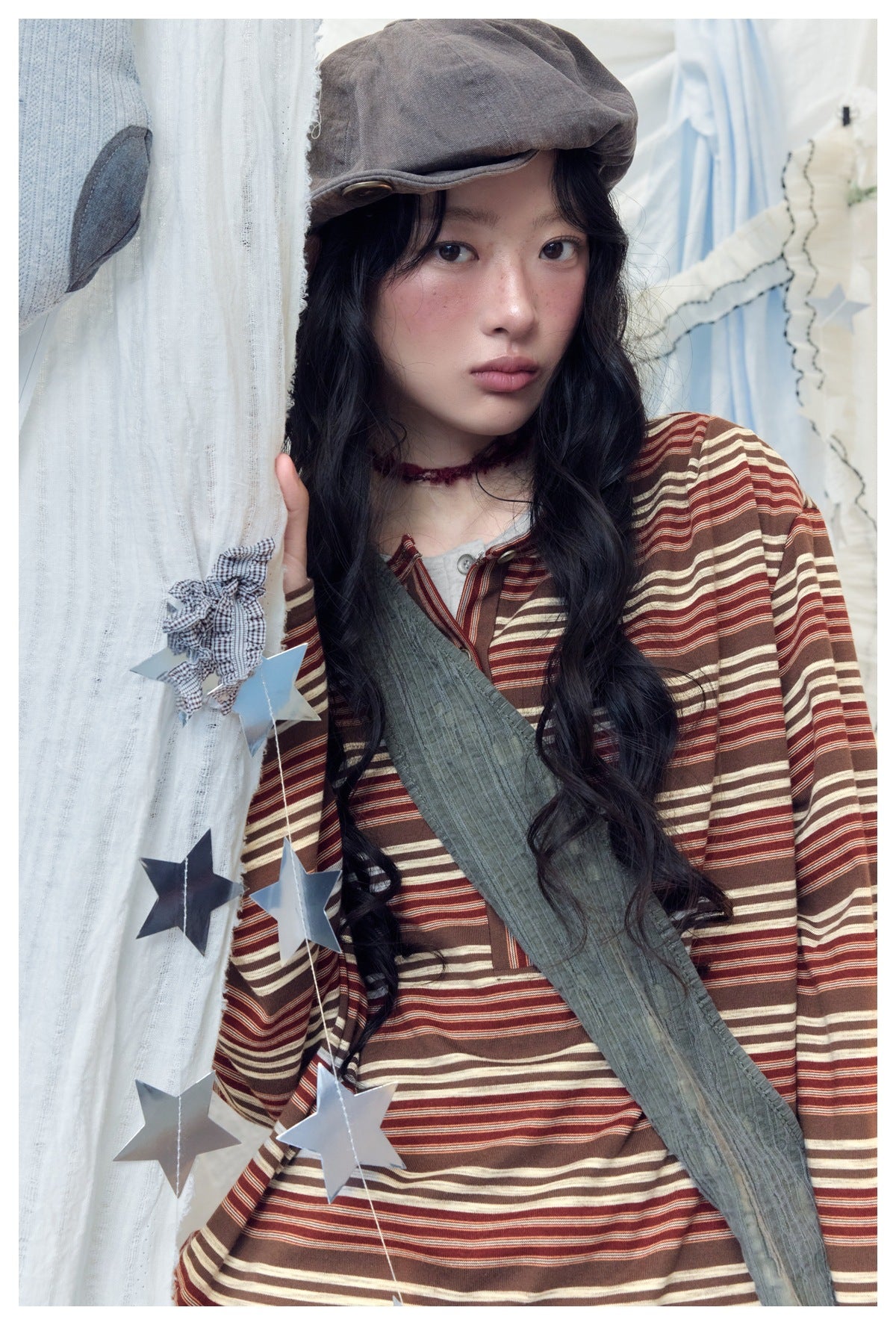 Close view of a model wearing a brown, rust and cream striped long-sleeve henley with a buttoned neckline.