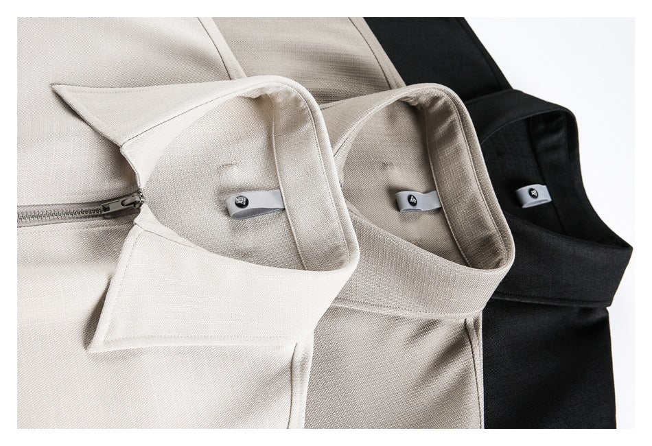Close-up of light and black collared shirts showing the fabric, zipper, and small interior label tabs.