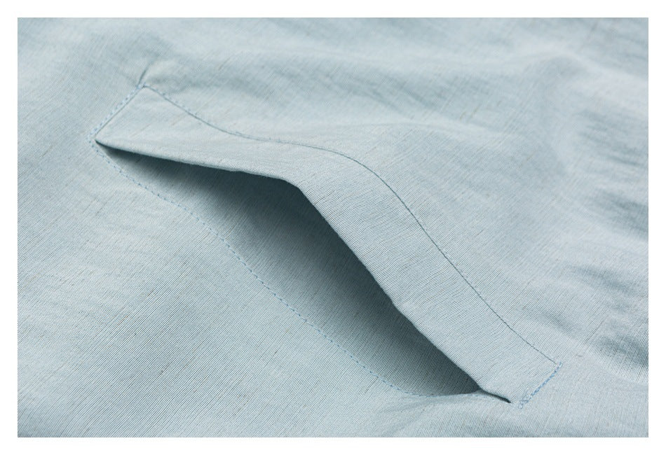 Close-up of an angled pocket opening and stitching on pale blue fabric.