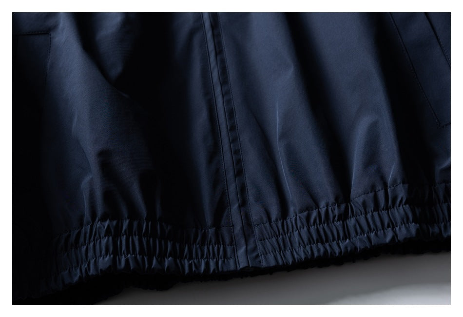Close-up of the navy jacket's gathered elastic hem and center seam.