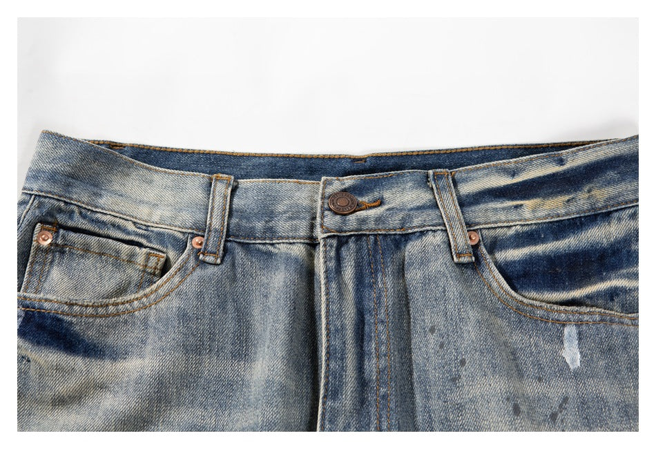 Close-up of blue faded jeans showing the front waistband, button, belt loops, fly, and front pockets.