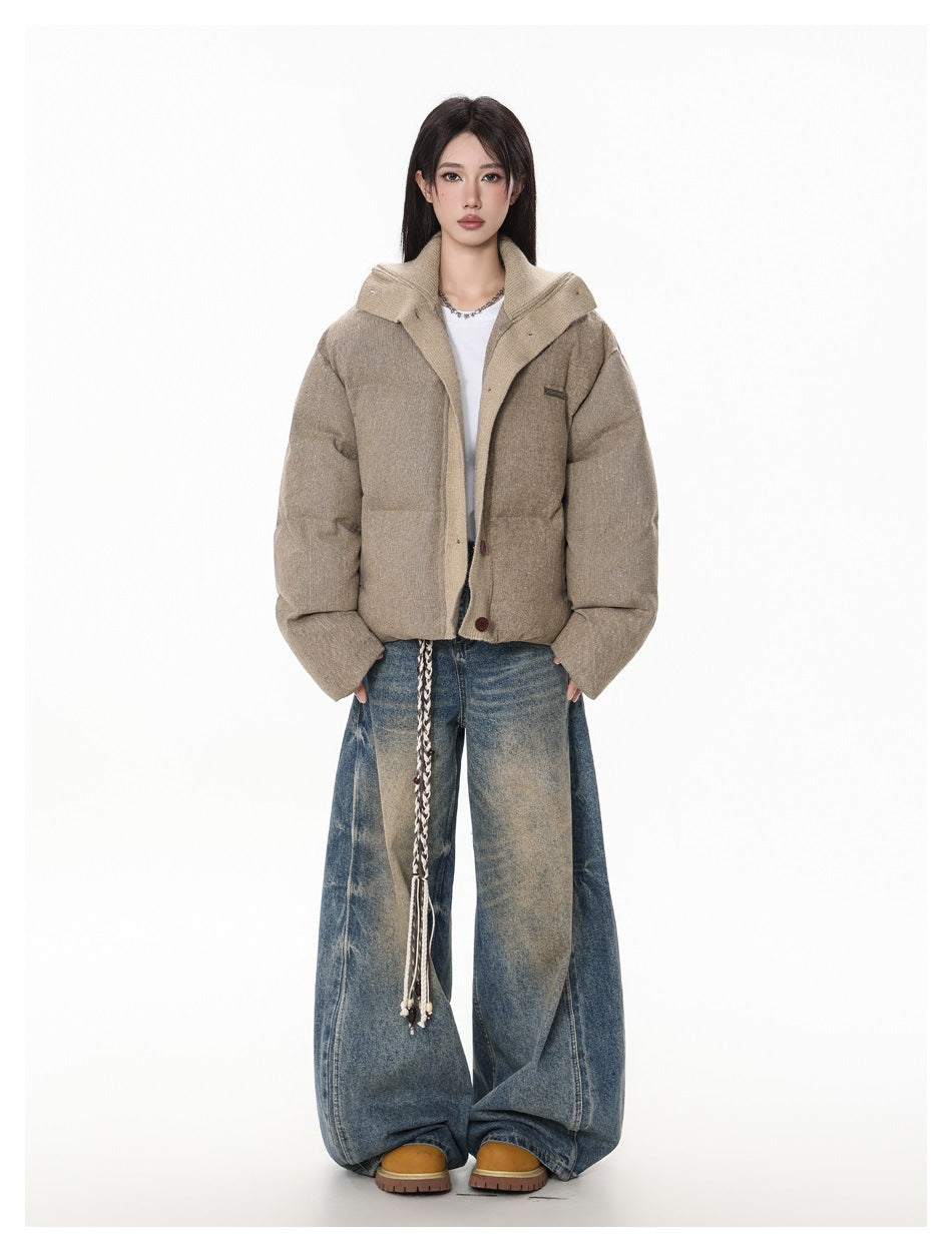 Full-length view of a woman in a cropped tan puffer jacket with knit collar, white top, faded wide-leg jeans and tan boots