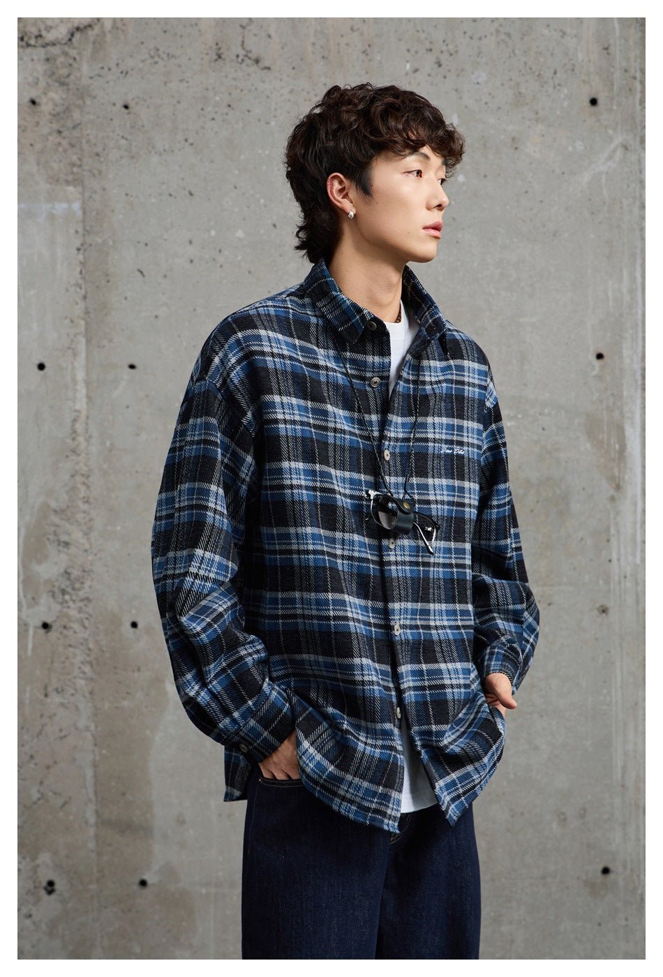 Model wearing a blue, black and white plaid button-up shirt over a white tee, shown from the front.