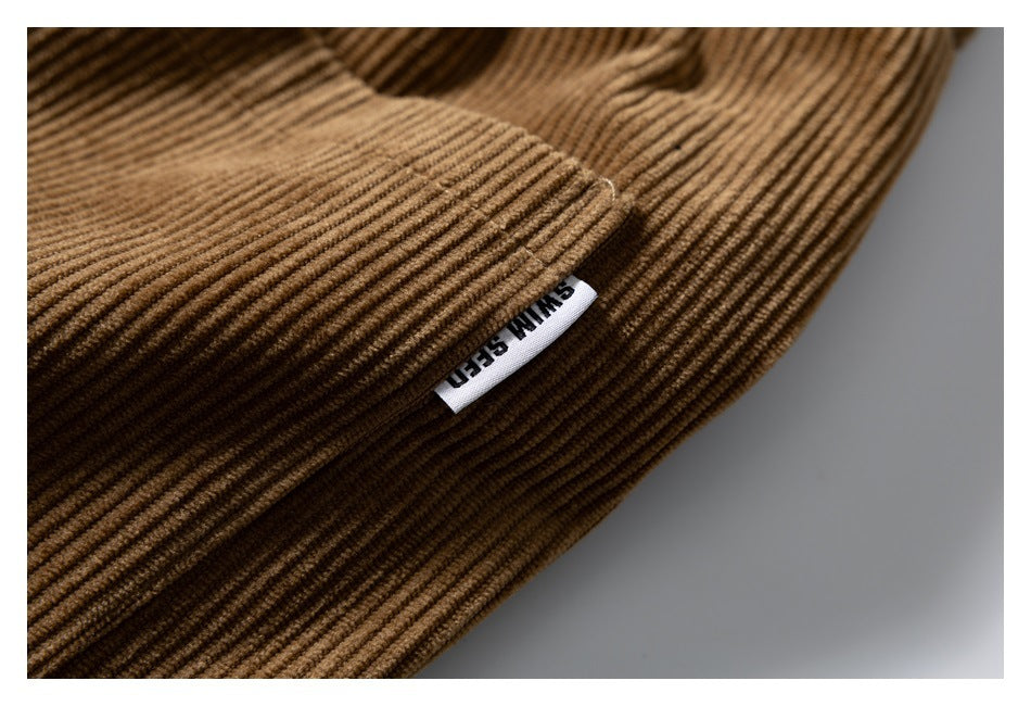 Close-up of brown corduroy fabric and a small sewn white label at a seam.