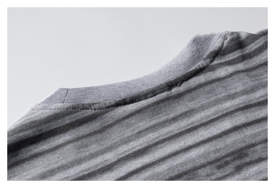 Close-up of the ribbed crew neckline and shoulder seam on a gray striped garment.