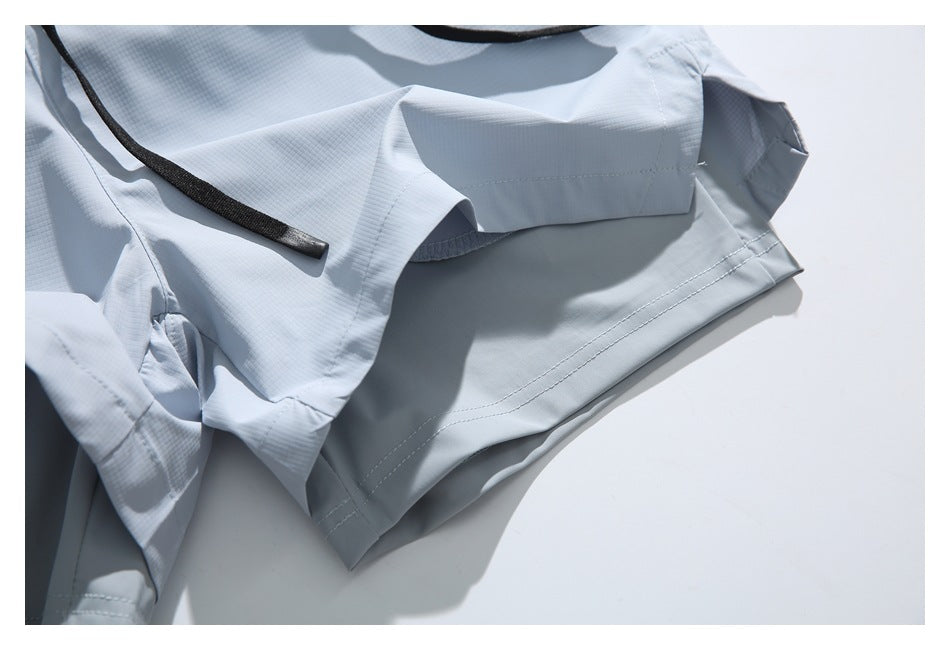 Close-up of a pale blue-gray garment laid flat, showing stitched panels and a black cord.