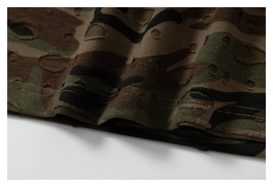 Close-up of a dark green, brown, and black camouflage garment hem with stitched seams.