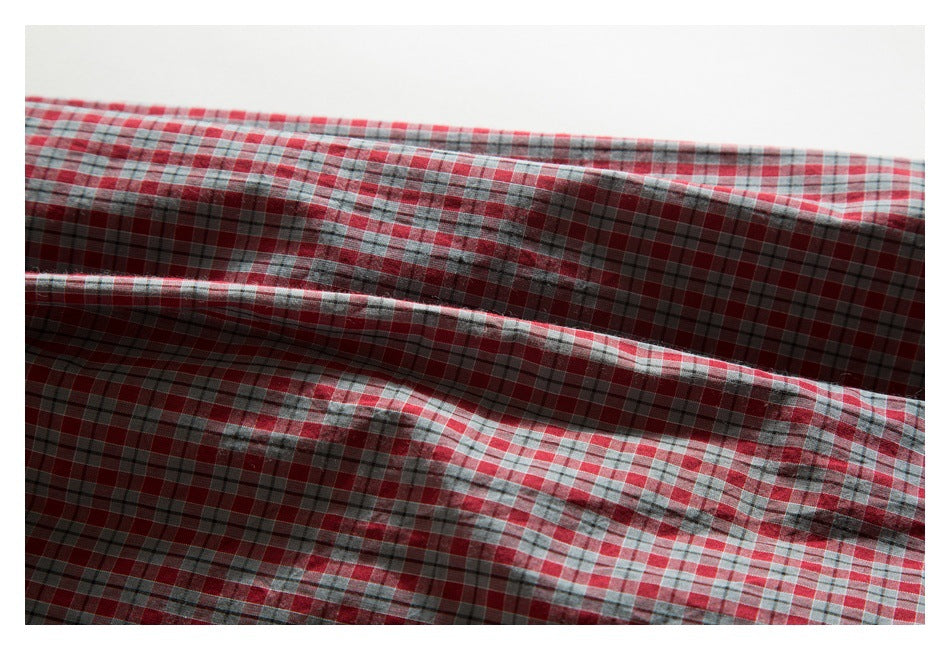 Close-up of the red, gray, and white checked shirt fabric, showing its plaid pattern and folds.