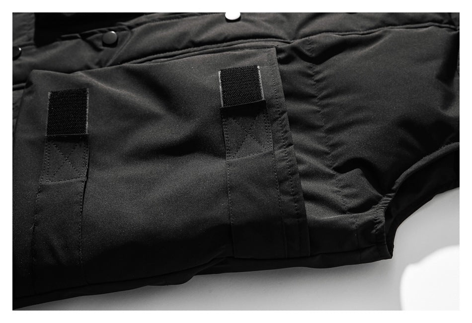 Close-up of a black jacket pocket with two vertical hook-and-loop fastening tabs.
